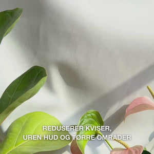 Nærbilde av en hånd som doserer en liten mengde lett, kremet body lotion med salisylsyre i håndflaten og masserer den inn i ru hud med tendens til urenheter: den glatte, raskt absorberende teksturen eksfolierer forsiktig døde hudceller, fukter med hyaluronsyre og melkesyre, og forbedrer hudens struktur med salisylsyre og niacinamid.